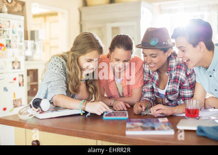 Un gruppo di ragazzi che usano insieme tavoletta digitale a tavola in cucina Foto Stock