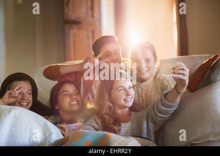 Un gruppo di ragazzi sorridenti tenendo selfie sul divano nel soggiorno Foto Stock