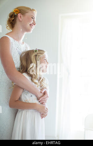 Sposa abbracciando damigella e guardando fuori della finestra Foto Stock