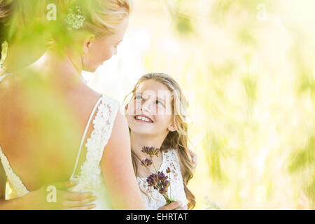 Sorridente damigella con fiori e sposa durante il ricevimento di nozze in giardino Foto Stock