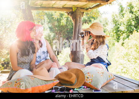 Tre ragazze adolescenti per scattare delle foto in tree house in presenza di luce solare Foto Stock