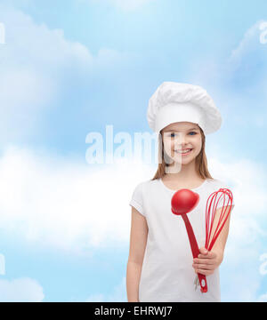 Ragazza sorridente in cook hat con siviera e frusta Foto Stock