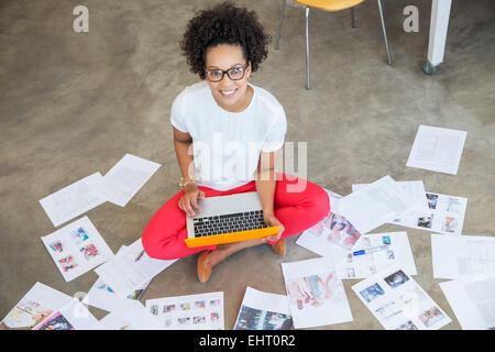 Giovane donna seduta sul pavimento e lavorare con il computer portatile Foto Stock