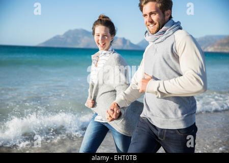 Coppia giovane tenendo le mani e camminando sulla spiaggia Foto Stock