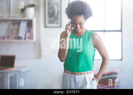 Ritratto di una donna con nero capelli ricci parlando al telefono cellulare Foto Stock