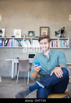 Bionda e giovane uomo seduto con il cellulare in studio Foto Stock