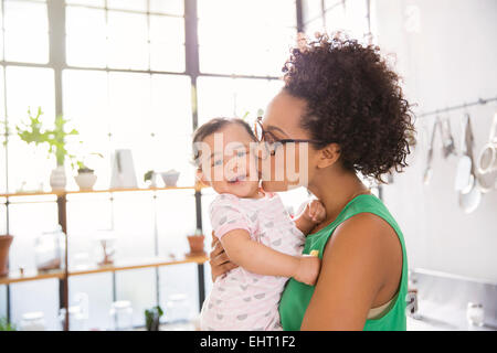 Madre baciando la sua figlia in cucina domestica Foto Stock