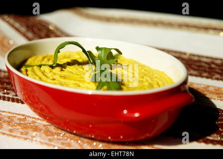 Humus pasta con olio e peperoncino, decorata con rucola Foto Stock