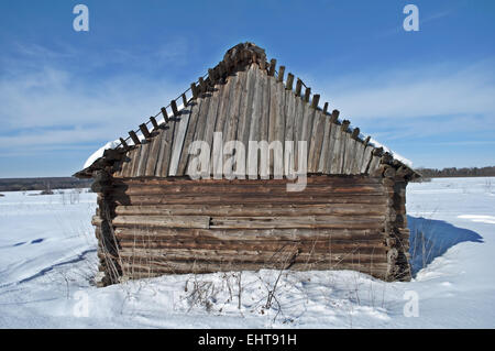 Il vecchio fienile in legno su un campo nevoso Foto Stock