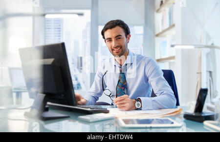 Ritratto di uomo seduto alla sua scrivania in ufficio Foto Stock