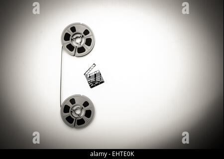 Due vintage 8mm bobine collegato verticalmente con film e un po' di clapper board in bianco e nero in stile vintage Foto Stock