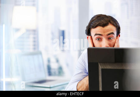 Uomo che utilizza il computer in ufficio,stressato e preoccupato Foto Stock