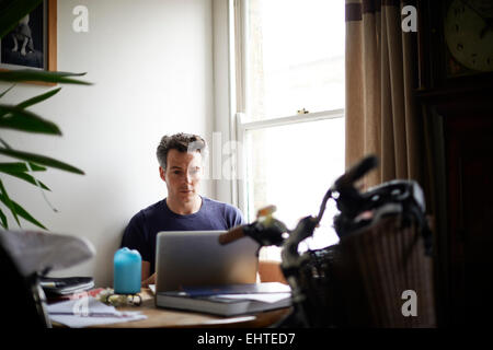 Uomo al lavoro su laptop a casa Foto Stock