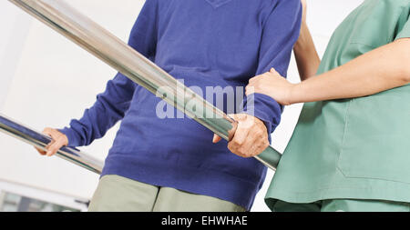 Le mani della vecchia donna sulle maniglie del tapis roulant in fisioterapia Foto Stock