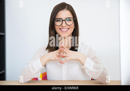 Felice imprenditrice seduta al tavolo in ufficio Foto Stock