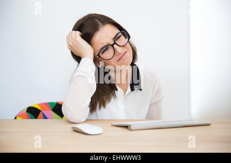 Stanco imprenditrice seduta al tavolo in ufficio Foto Stock
