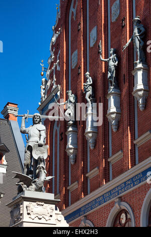 Facciata in mattoni rossi con le sculture della Casa delle Teste Nere su uno sfondo di cielo blu nella riga. Lettonia Foto Stock