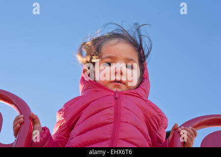 Adorabili poco sulla parte superiore della slitta nel parco giochi una fredda giornata di sole di inverno Foto Stock