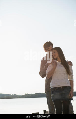 Coppia giovane abbracciando il tramonto romantico lago Foto Stock