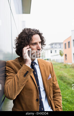 Ritratto giovane uomo capelli lunghi tuta telefono cellulare Foto Stock