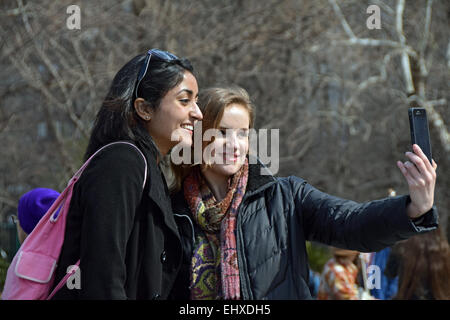 Due belle donne che prendono un selfie vicino alla fontana di Washington Square Park nel Greenwich Village di New York City Foto Stock