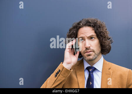 Giovane imprenditore bello capelli lunghi telefono cellulare Foto Stock