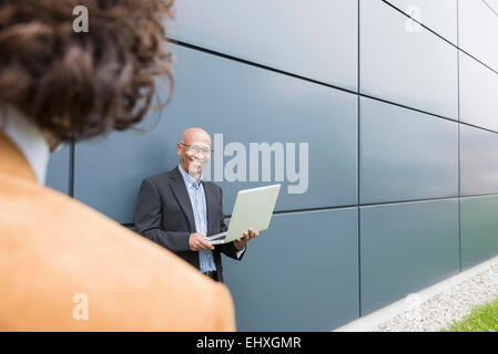 Due imprenditori africani parlare caucasica laptop Foto Stock