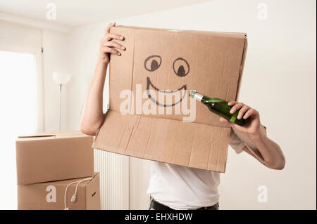 Uomo che indossa faccia felice scatola di movimentazione sopra la testa e fingere di bere birra, Baviera, Germania Foto Stock