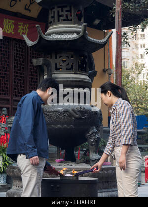 Illuminazione persone joss stick incenso presso il Tempio del Buddha di Giada a Shanghai in Cina Foto Stock