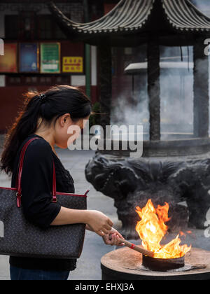 Illuminazione donna joss stick di incenso e di pregare presso il Tempio del Buddha di Giada a Shanghai in Cina Foto Stock