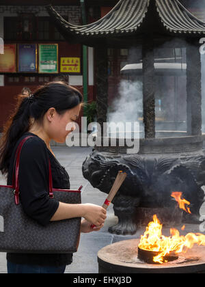 Donna che mantiene joss stick di incenso e di pregare presso il Tempio del Buddha di Giada a Shanghai in Cina Foto Stock