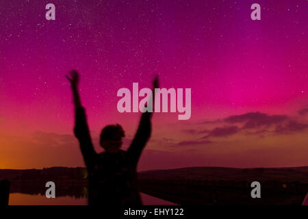 Silhouette di donna sotto l aurora boreale (Northern lights) visto su Usk serbatoio nel Parco Nazionale di Brecon Beacons, Galles Foto Stock