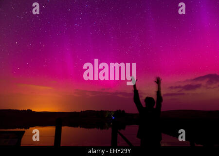 Silhouette di donna sotto l aurora boreale (Northern lights) visto su Usk serbatoio nel Parco Nazionale di Brecon Beacons, Galles Foto Stock