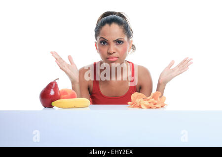 Bella giovane donna scegliere tra frutta e patate fritte Foto Stock