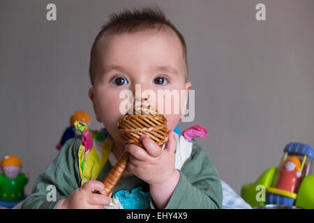 8 mese fa Baby girl, circondato da giocattoli in baby bouncer, pianto Foto Stock