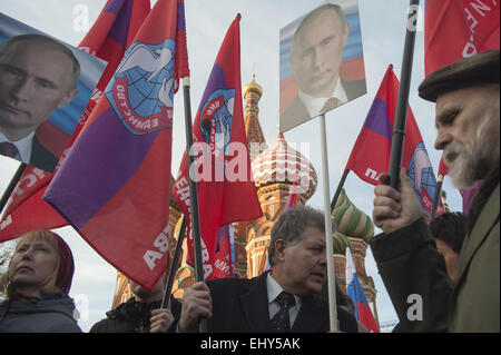 Mosca, Russia. Xviii Mar, 2015. Le persone in attesa di bandiere e di ritratti del presidente russo Vladimir Putin durante un rally dedicato a un anno di anniversario di annessione di Ucraina la penisola di Crimea a Mosca, in Russia. Cattedrale di San Basilio è visto in background. © Anna Sergeeva/ZUMA filo/Alamy Live News Foto Stock