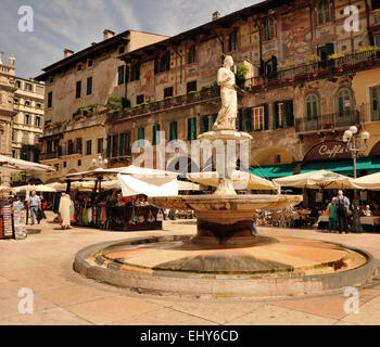 Un ampia veduta di Piazza delle Erbe, Verona, Italia, con la Madonna Verona fontana e i visitatori e i turisti in una strada del mercato allestito nella piazza. Foto Stock