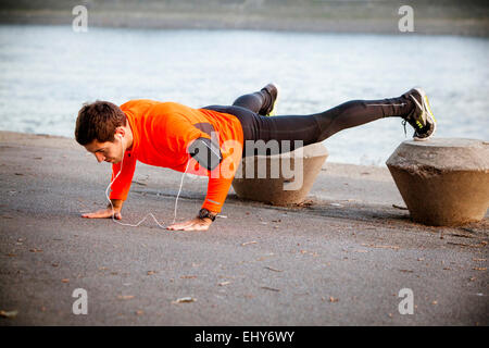 Runner maschio facendo push-up sul lungomare Foto Stock