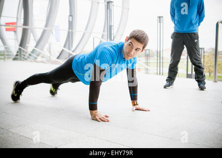 Runner maschio facendo push-up in città Foto Stock