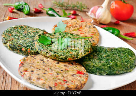 Alcune diverse materie veggie hamburger in una piastra su una tavola in legno rustico Foto Stock