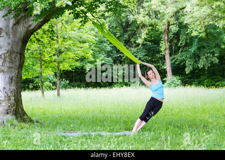 Giovane donna fa esercizi di stretching con fascia di gomma, Monaco di Baviera, Germania Foto Stock