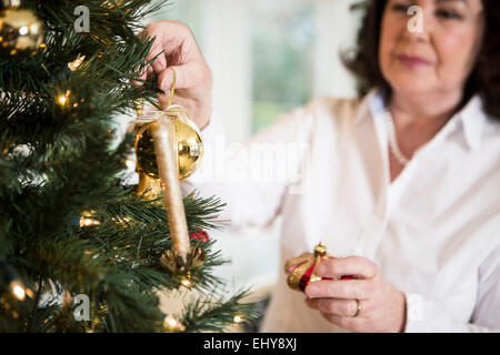 Senior donna decorare albero di Natale Foto Stock