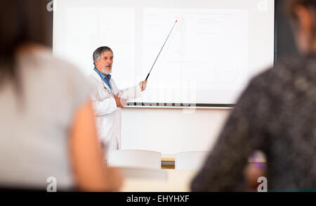 Senior professore di chimica dando una lezione nella parte anteriore dell'aula piena di studenti (SHALLOW DOF; dai toni di colore immagine) Foto Stock