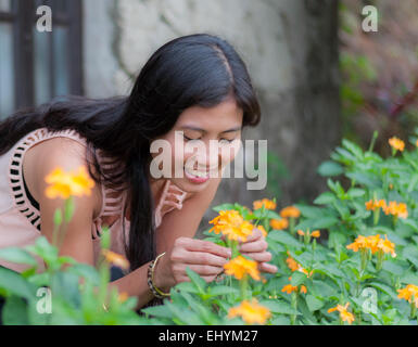 Giovane donna a caccia di fiori nel giardino Foto Stock