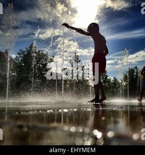 Silhouette di un ragazzo in piedi di una fontana di acqua, Niort, Francia Foto Stock
