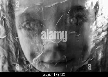 Ritratto di una ragazza che guarda attraverso una tenda a rete Foto Stock