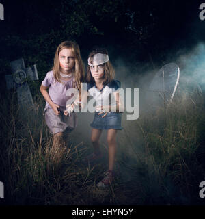 Due ragazze fingendo di essere zombie in un cimitero di Halloween Foto Stock