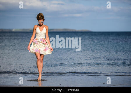 Giovane donna camminando lungo la spiaggia Foto Stock