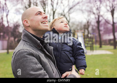 Padre bambino portando il figlio e guardando in alto Foto Stock