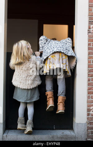 Due ragazze che cercano di salire su una porta olandese Foto Stock